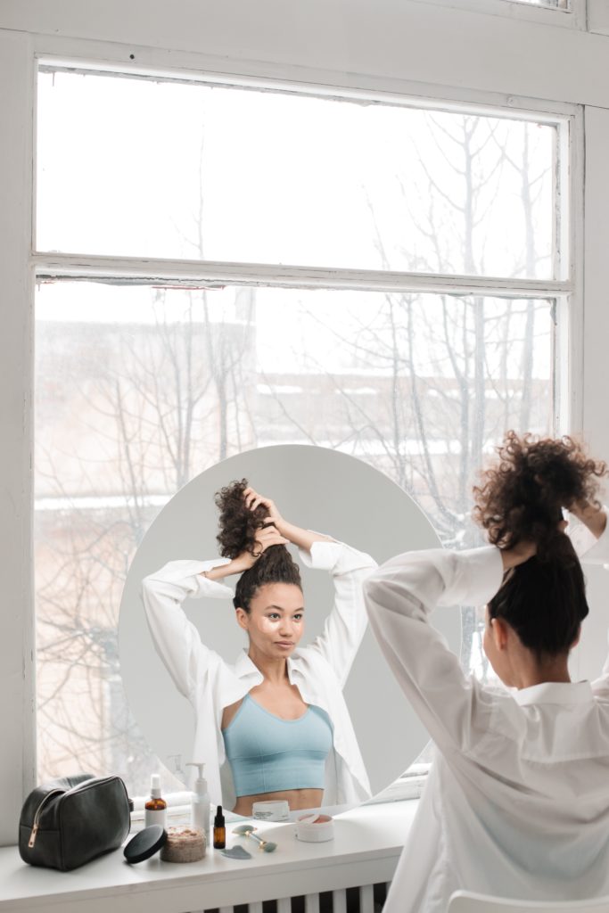 woman styling hair in front of mirror