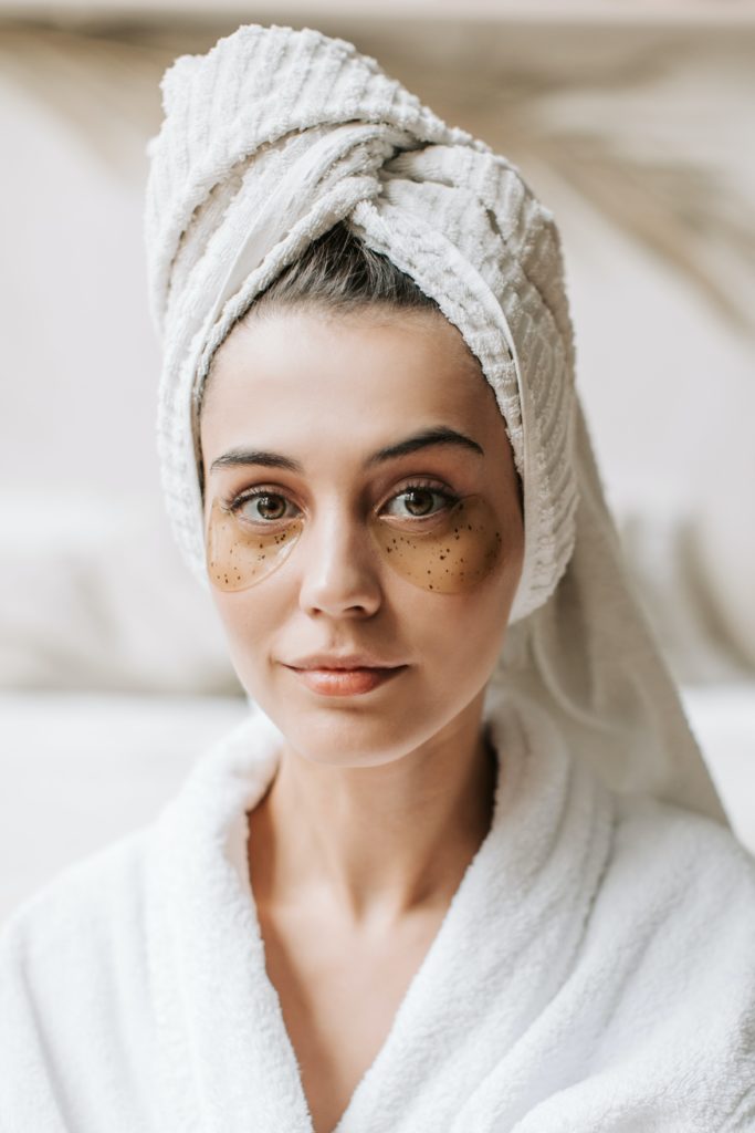woman with hair wrapped in towel wearing under eye strips