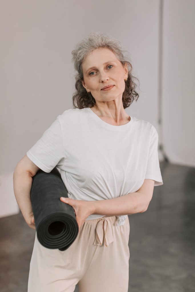 woman holding rolled up yoga mat
